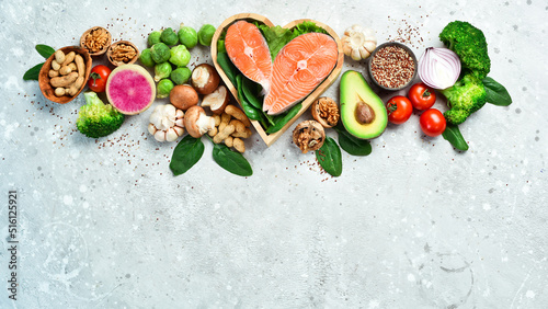 The concept of healthy food: nuts, salmon, avocados, spinach, mushrooms, berries. On a stone background. Top view. Copy space.