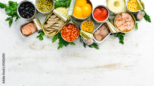 Food background in tin cans. Canned vegetables  beans  fish and fruits on a white wooden background. Top view.