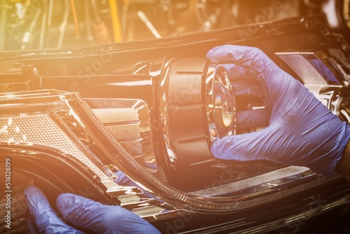 A mechanic wearing rubber gloves installs an LED lens into the headlight housing.Car headlight during repair and cleaning.The mechanic restores the headlight of the car.Restoration of automotive optic photo