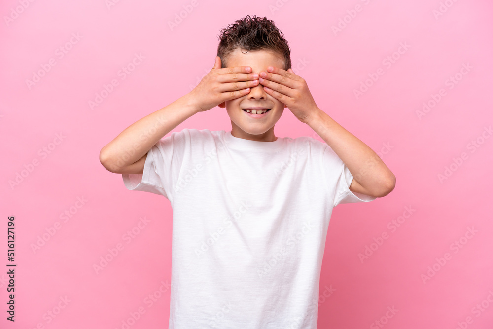 Little caucasian boy isolated on pink background covering eyes by hands and smiling Little caucasian boy isolated on pink background covering eyes by hands and smiling