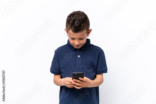 Little caucasian boy isolated on white background sending a message with the mobile