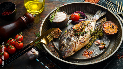 Foto Baked dorado fish with asparagus and vegetables in a metal tray