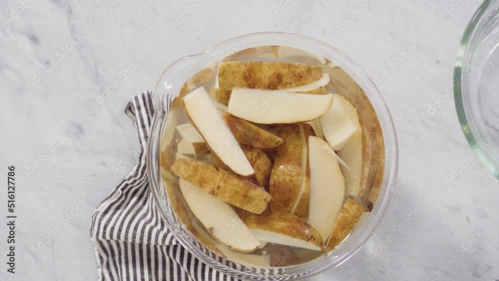 Flat lay. Step by step. Soaking potato wedges in a bowl of water to prepare baked potato wedges with spices. Flat lay. Step by step. Soaking potato wedges in a bowl of water to prepare baked potato wedges with spices.