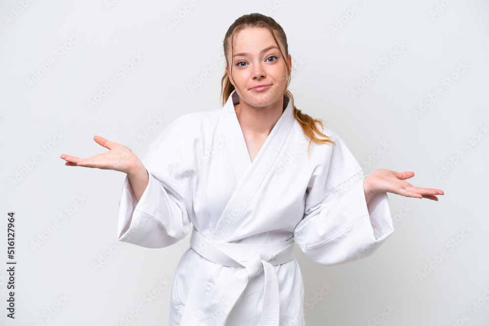 Young caucasian girl doing karate isolated on white background having doubts while raising hands Young caucasian girl doing karate isolated on white background having doubts while raising hands