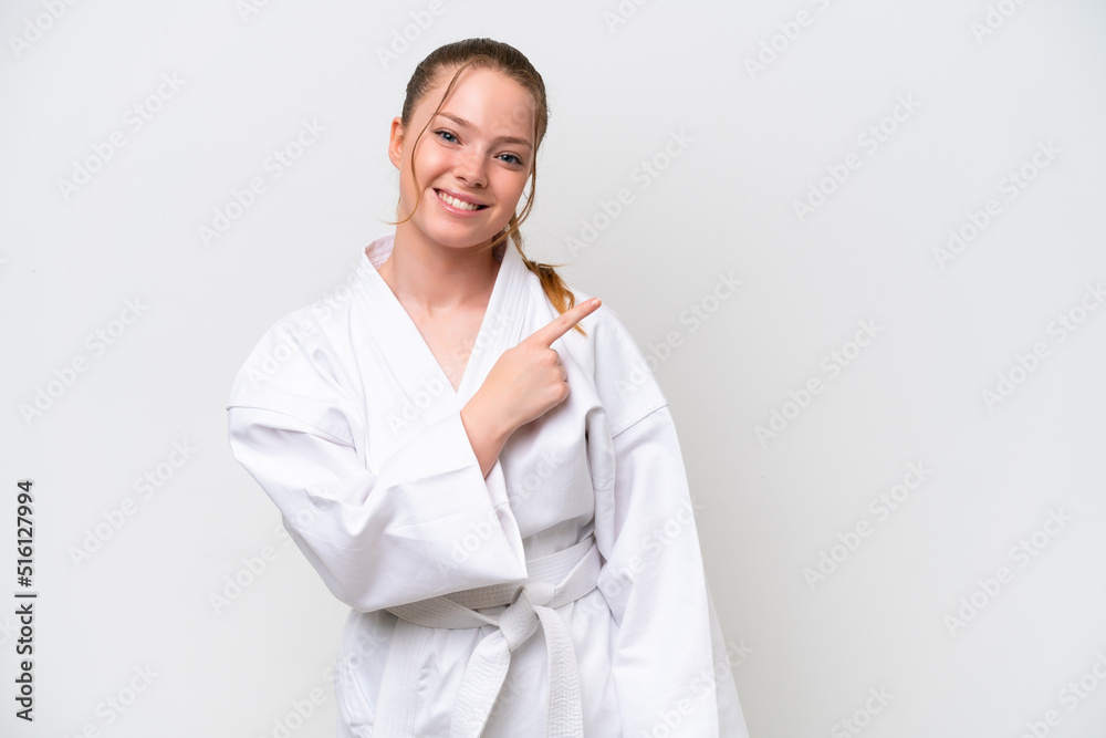 Young caucasian girl doing karate isolated on white background pointing to the side to present a product Young caucasian girl doing karate isolated on white background pointing to the side to present a product