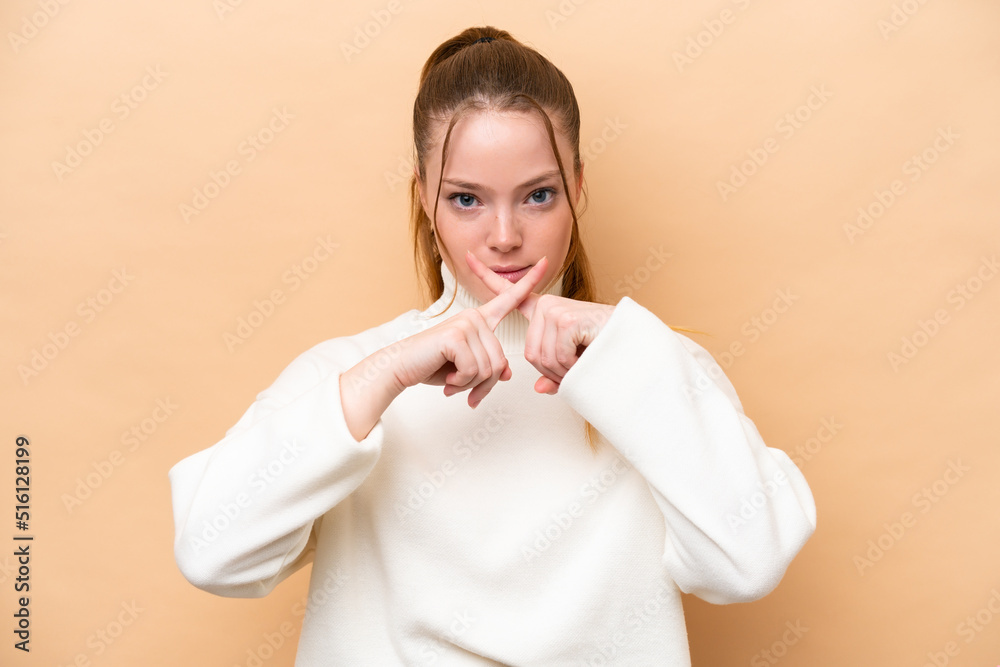 Young caucasian woman isolated on beige background showing a sign of silence gesture Young caucasian woman isolated on beige background showing a sign of silence gesture