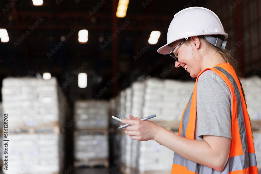 Fototapeta premium Female worker using digital tablet checking cargo shipment at courier distribution shipping dock