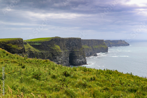 Stunning Cliffs of Moher scenery with ocean and green hill covered cliffs alongside the wild Atlantic way in County Clare Ireland