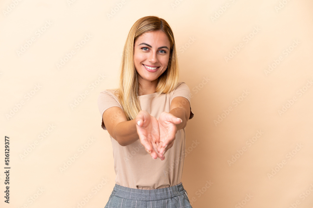 Obraz premium Blonde Uruguayan girl isolated on beige background holding copyspace imaginary on the palm to insert an ad