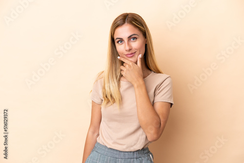Blonde Uruguayan girl isolated on beige background thinking