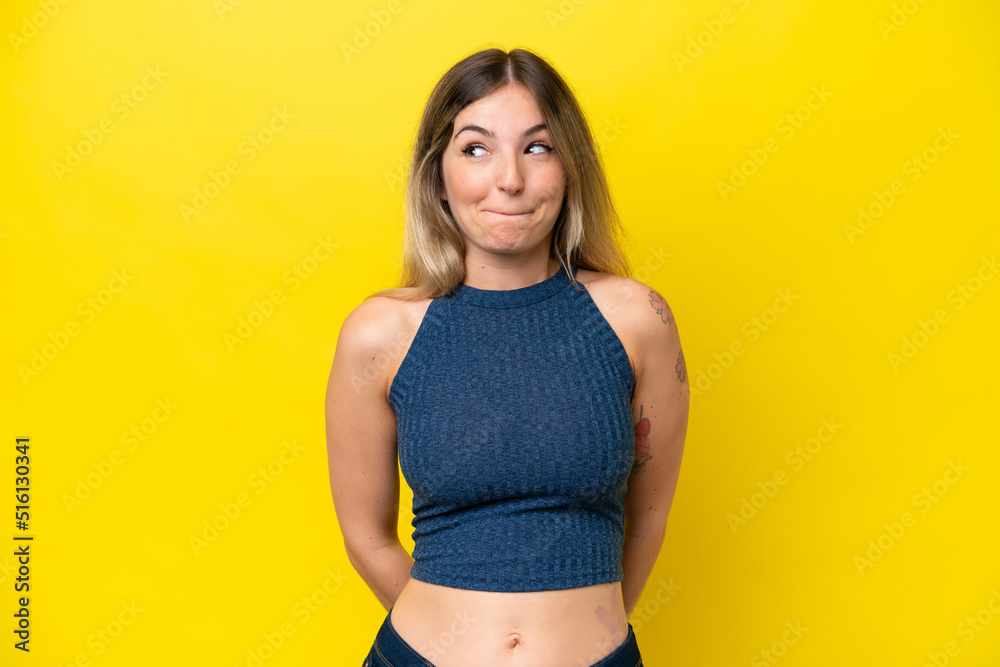 Obraz premium Young Rumanian woman isolated on yellow background having doubts while looking up