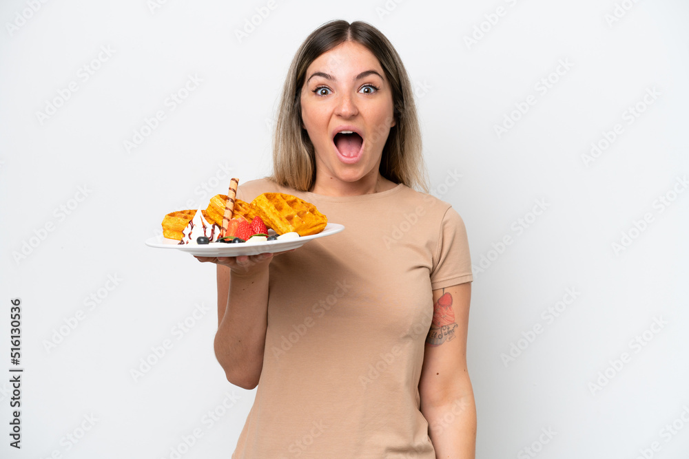 Young Rumanian woman holding waffles isolated on white background with surprise and shocked facial expression Young Rumanian woman holding waffles isolated on white background with surprise and shocked facial expression