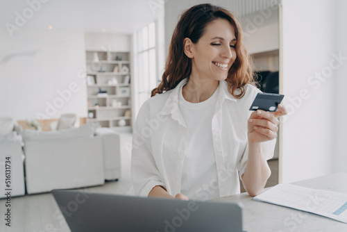 Happy european girl is holding credit card and going to buy online. Purchasing through internet.