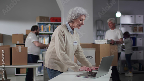 Senior woman working on computer in volunteer center photo