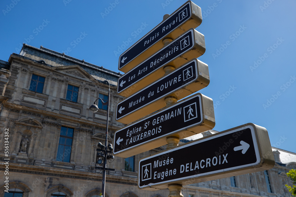 panneaux de signalisation indiquant des lieux célèbres dans Paris comme le musée du Louvre, le Palais Royal ou le musée Delacroix