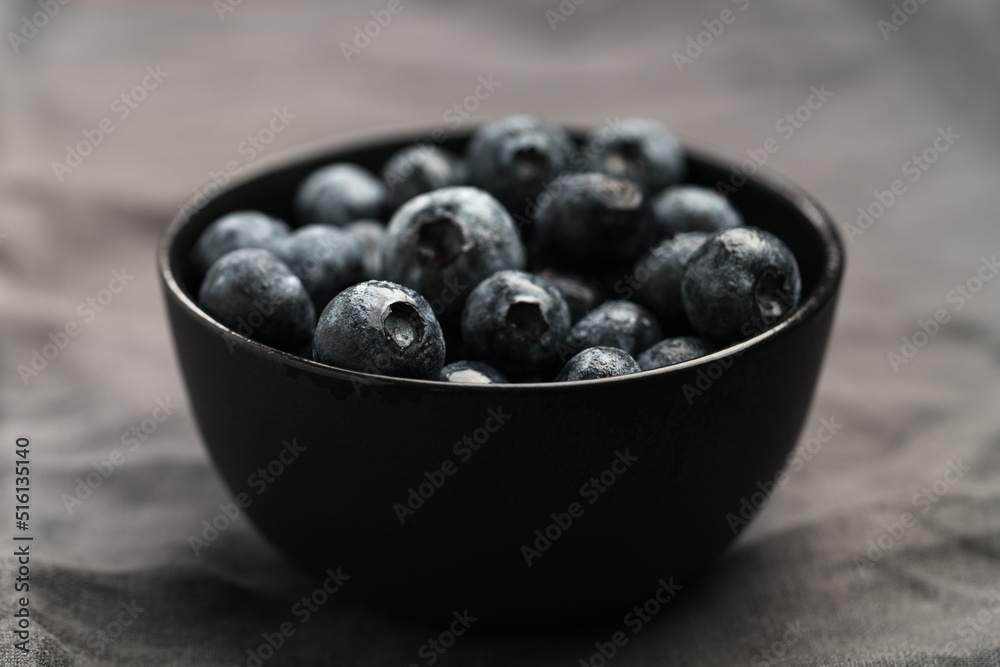 Freshly washed organic blueberries in a black bowl closeup