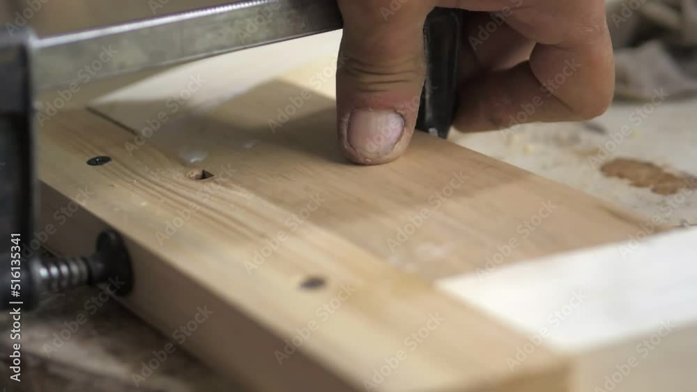 Slow motion. Close-up of a carpenter tightening two screw clamps to a piece of light wood. A professional carpenter collects furniture parts from wood.Assembling furniture in a carpentry workshop. Slow motion. Close-up of a carpenter tightening two screw clamps to a piece of light wood. A professional carpenter collects furniture parts from wood.Assembling furniture in a carpentry workshop.