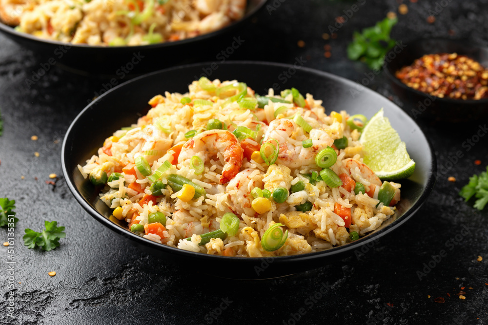 Prawn fried rice with eggs and vegetables in black bowl. Healthy asian food. Prawn fried rice with eggs and vegetables in black bowl. Healthy asian food.