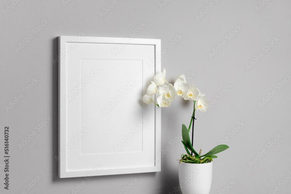 Blank vertical frame mockup with white orchid flower Blank vertical frame mockup with white orchid flower