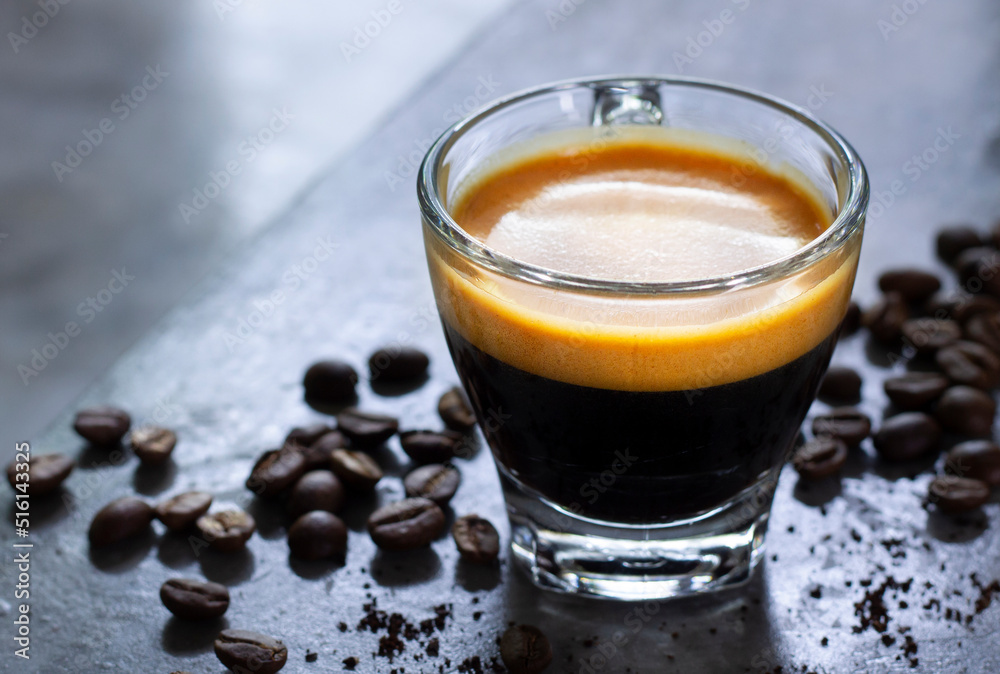 cup of hot espresso with a nice crema on a rustic concrete table with a pile of roasted arabica coffee. cup of hot espresso with a nice crema on a rustic concrete table with a pile of roasted arabica coffee.
