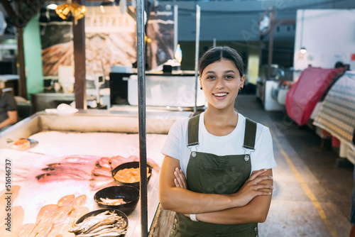 Female fishmonger standing near seafood shop counter