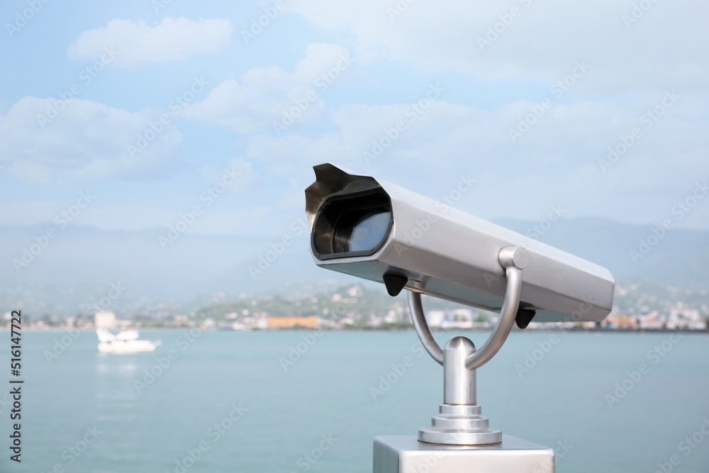 Metal tower viewer installed near sea, space for text. Mounted binoculars