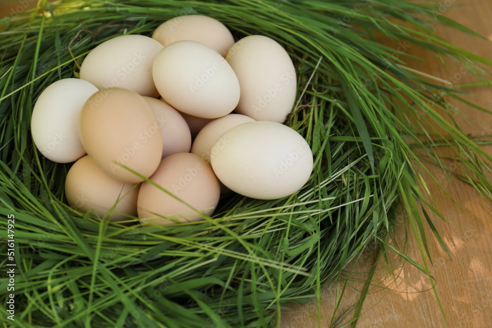 Nest made of green grass with fresh raw eggs on wooden table, closeup Nest made of green grass with fresh raw eggs on wooden table, closeup