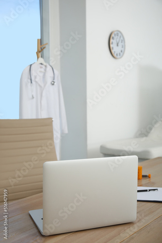 Modern laptop on wooden table in medical office. Interior design © New Africa