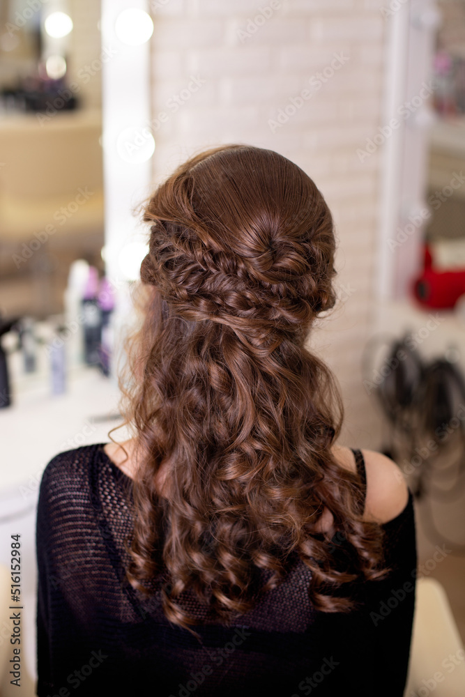 Female back with curly, brunette hair in hairdressing salon
