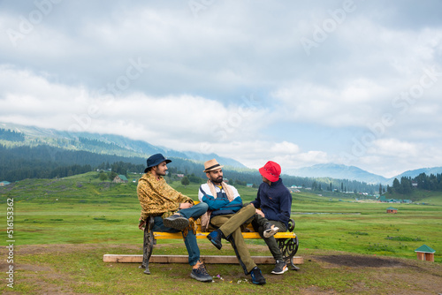 Three Young man on a mountain top sitting on bench, Gulmarg, Jammu and Kashmir, India.