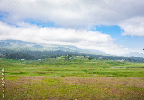 Panorama of beautiful countryside of India. sunny afternoon. wonderful springtime landscape in mountains. grassy field and rolling hills. rural scenery of Gulmarg. Jammu and Kashmir.