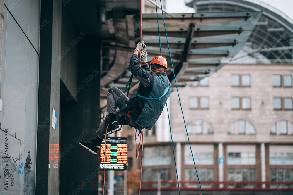 Industrial climber in uniform and helmet rises Industrial climber in uniform and helmet rises