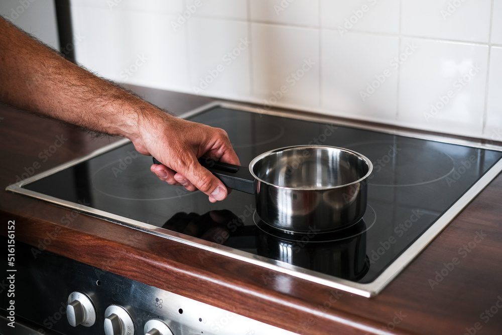 an adult man puts a ladle of water on the stove to cook spaghetti an adult man puts a ladle of water on the stove to cook spaghetti