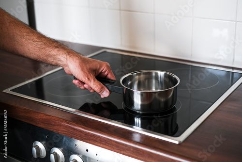 an adult man puts a ladle of water on the stove to cook spaghetti