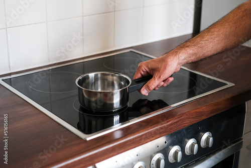 an adult man puts a ladle of water on the stove to cook spaghetti