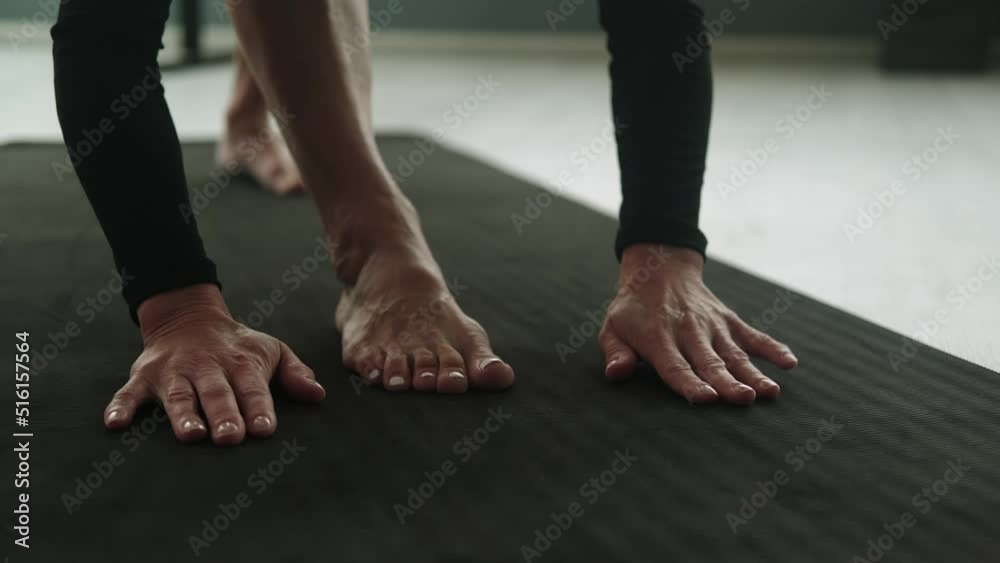 Yoga mat: An unidentified woman practices yoga in the studio, only her hands and feet are on the mat in the frame. Stretching: training on a sports mat. Close-up. Sports Equipment Yoga mat: An unidentified woman practices yoga in the studio, only her hands and feet are on the mat in the frame. Stretching: training on a sports mat. Close-up. Sports Equipment