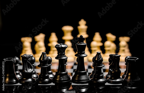 Close up of Chess pieces on a reflective mirror board surface with black background