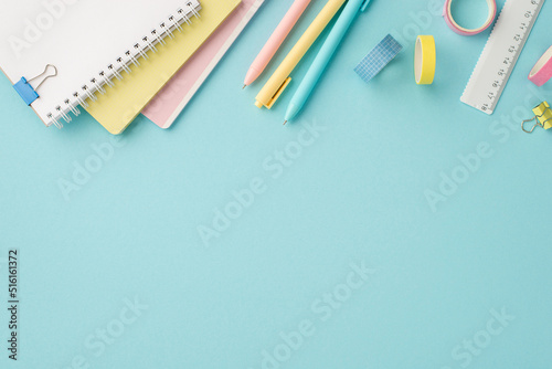 Back to school concept. Top view photo of school accessories stack of diaries colorful pens adhesive tape ruler and binder clips on isolated pastel blue background with empty space