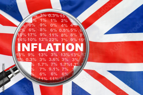 Magnifying glass focused on the word inflation on UK flag background. Hike interest rate. Inflation income crisis. Inflation, tax, cash flow and another financial concept in Britannia