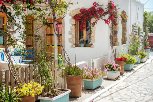 Cozy Greek house decorated with Petunia, bougainvillea and other beautiful flowers. Typical street in Lerapetra - seaside town in the southern part of Crete island, Greece. © RasaBasa