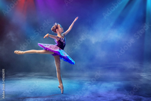 A little Japanese ballerina dances on stage in a lilac tutu on pointe shoes classical ballet.