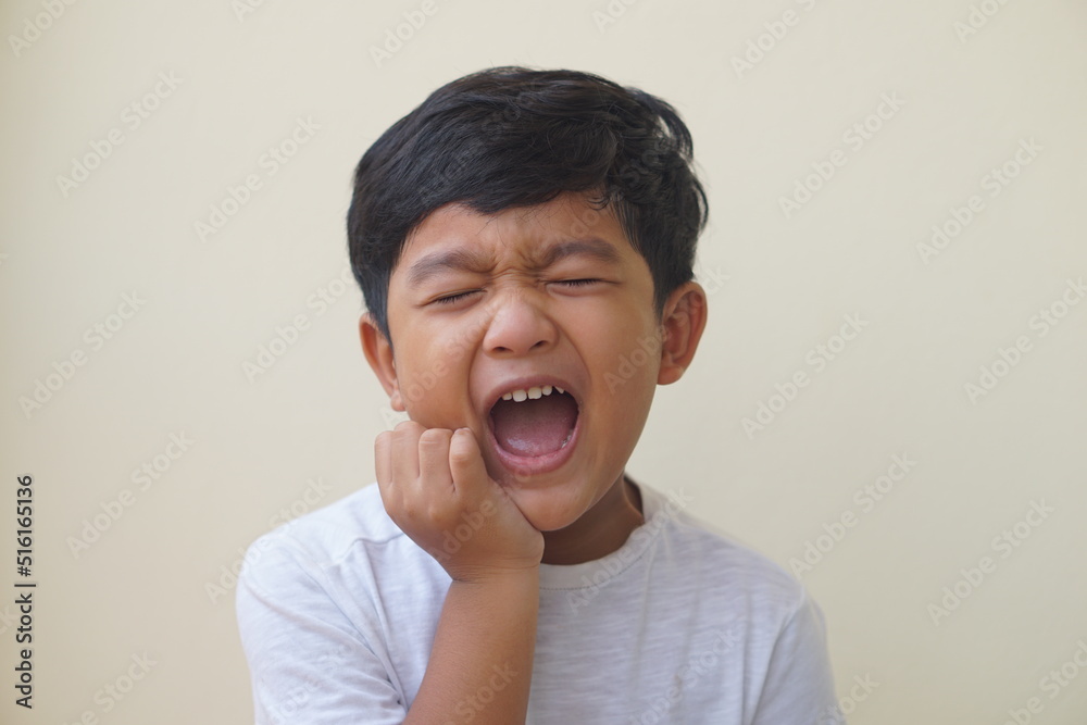 Little Asian boy 5 year old suffering from toothache pain while eating candy, holding his cheek, dental pain and he feel so sad. Little Asian boy 5 year old suffering from toothache pain while eating candy, holding his cheek, dental pain and he feel so sad.