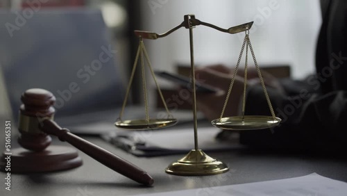 Online Legal Consultation Concept Lawyer prints an internet message on a laptop with a judge's scale and hammer on the table. photo