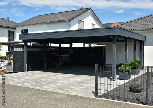 Fotografie Carport für zwei Autos aus beschichtetem Metall vor einem Wohnhaus