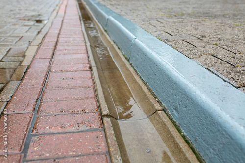 Rainwater runoff during rain. Concrete gutter for rainwater drainage between the sidewalk and the roadway.