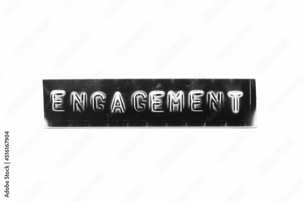 Embossed letter with word engagement in black banner on white paper background Embossed letter with word engagement in black banner on white paper background