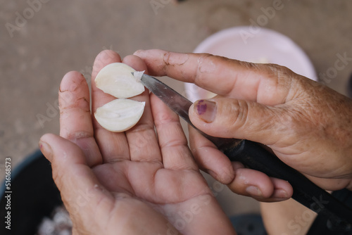 Macro photography or close up image of a group of garlic and garlic slices on a wooden cutting board and a knife on the side