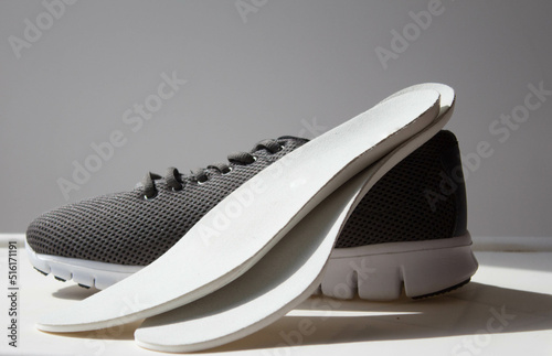 Leather orthopedic insoles located on the gray sport shoe.  Treatment and prevention of flat feet and foot diseases.