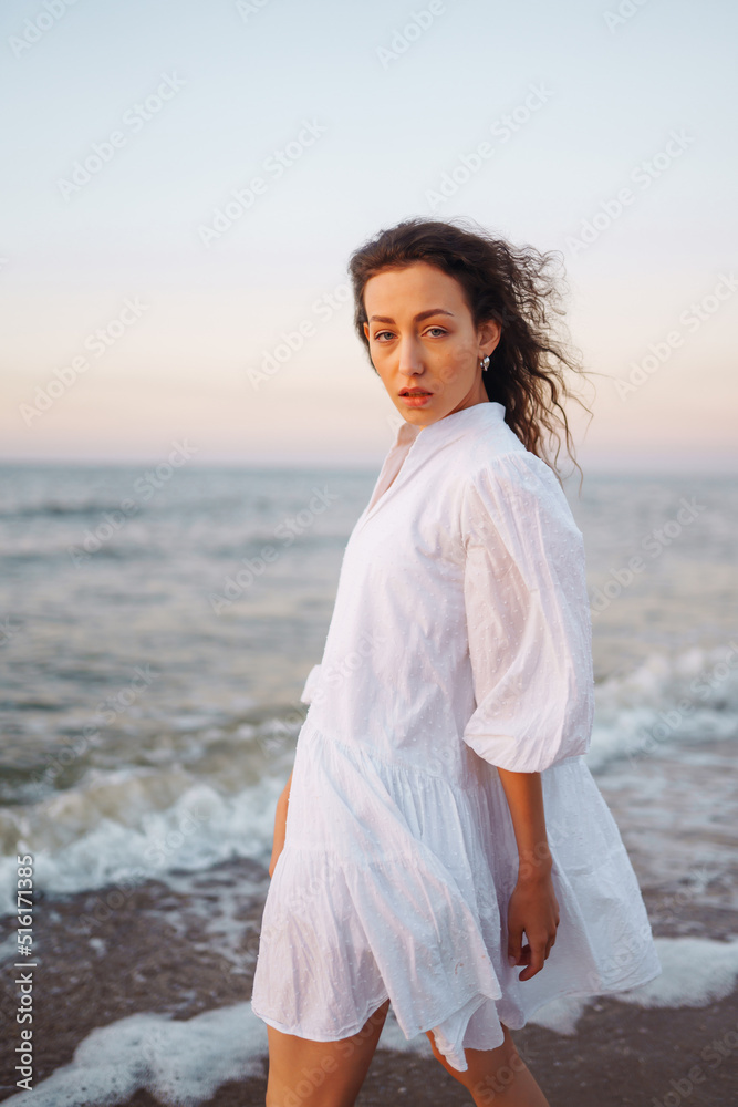 Stylish woman in elegant white dress posing near the sea. People, freedom, lifestyle, travel and vacations concept. Stylish woman in elegant white dress posing near the sea. People, freedom, lifestyle, travel and vacations concept.