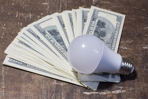 Economical light bulb on banknotes. Rising electricity prices
